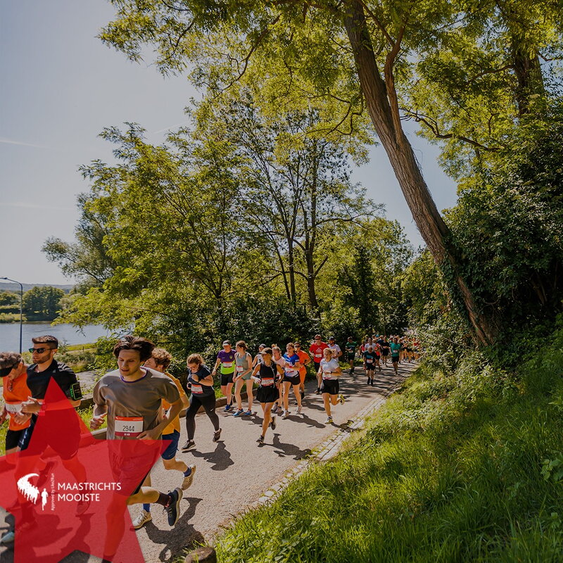 Participants in Maastrichts Mooiste run through the city park in Maastricht. A group of more than 30 runners passes by.
