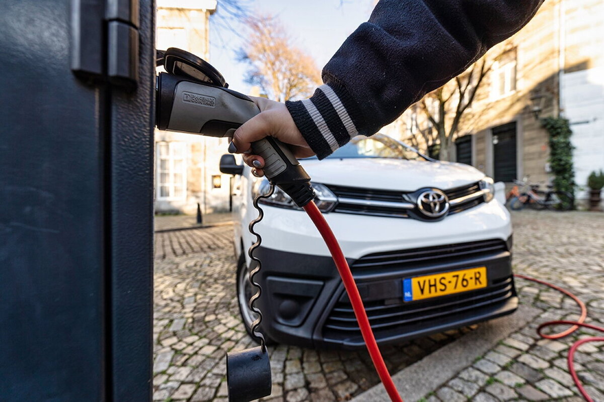 hand van iemand die zijn elektrische auto oplaadt bij de laadpaal