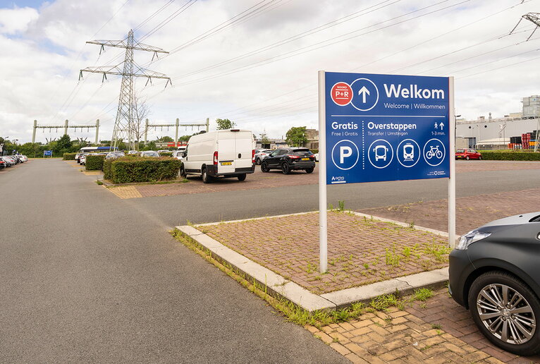Panneau de bienvenue au parking P+R Maastricht Nord, visible à l’entrée. Il indique parking gratuit et correspondance avec train, bus et vélo partagé. On voit quelques voitures garées dans les emplacements.