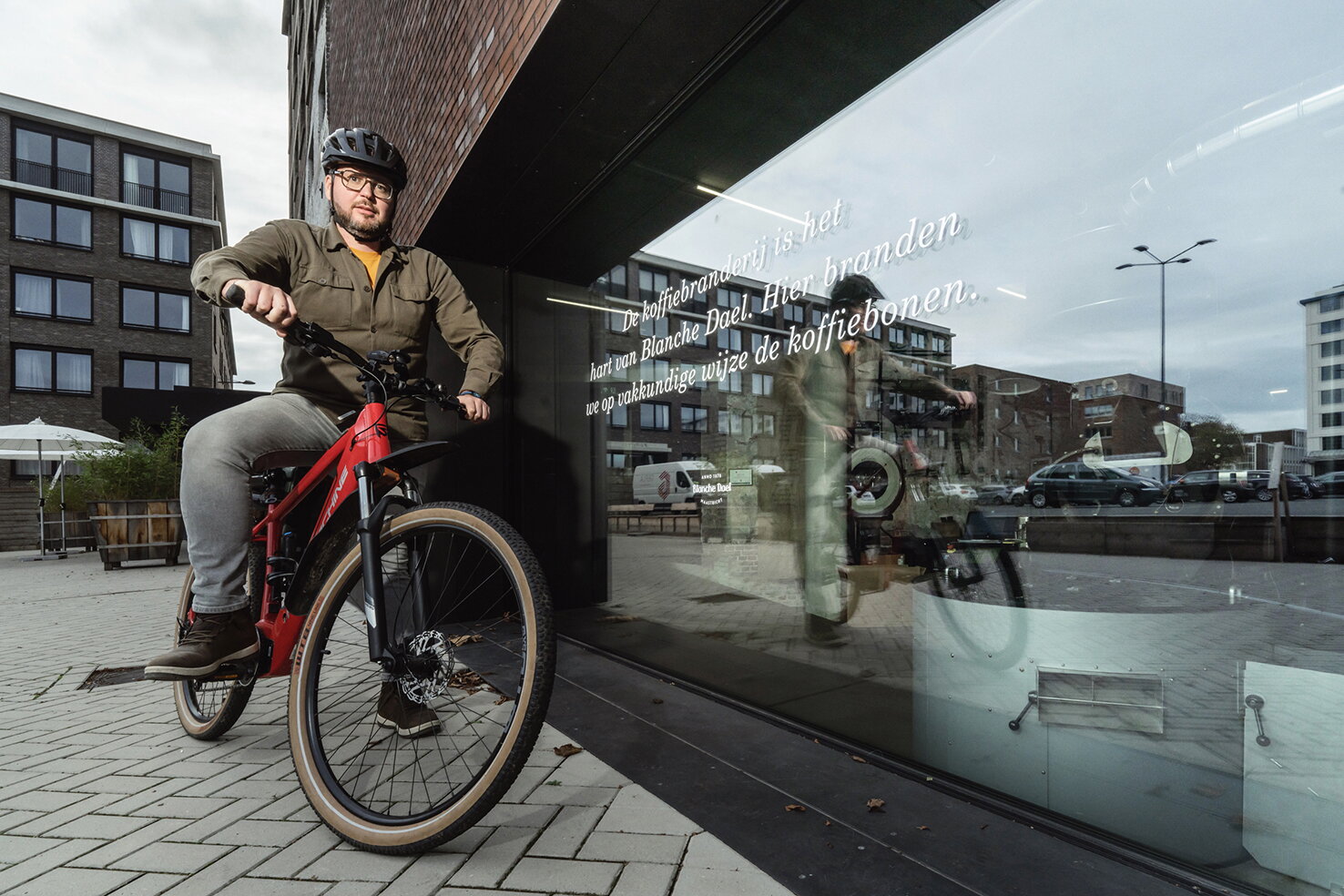 Richard Limpens op zijn rode fiets bij de etalage van Blanche Dael