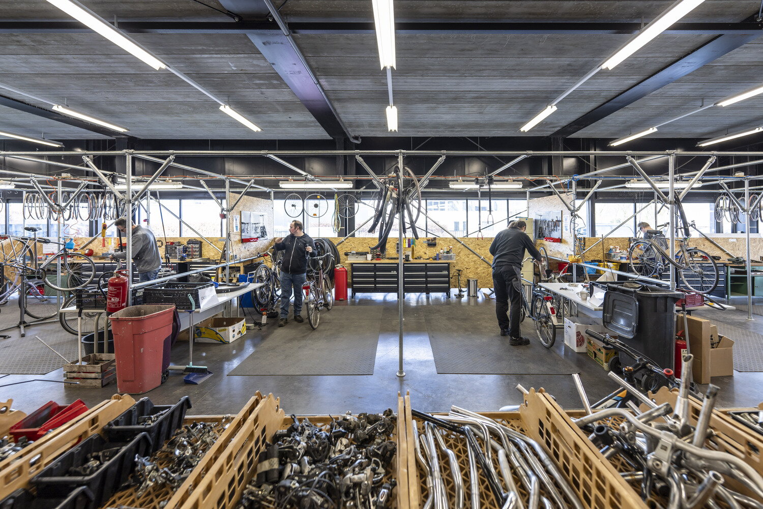 Meerdere mannen die kapotte fietsen aan het repareren zijn in het Ambachtscentrum Fiets