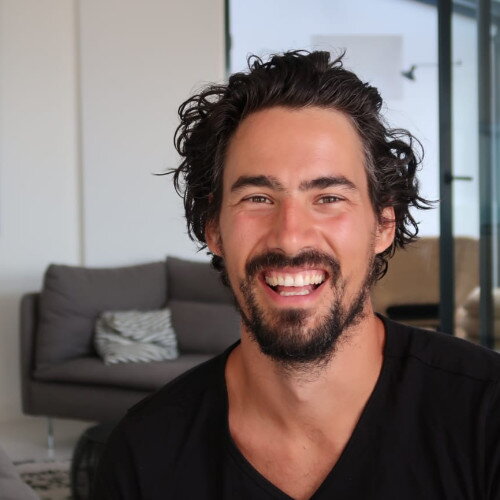 Portretfoto van Bas Urlings voor een grijze bank