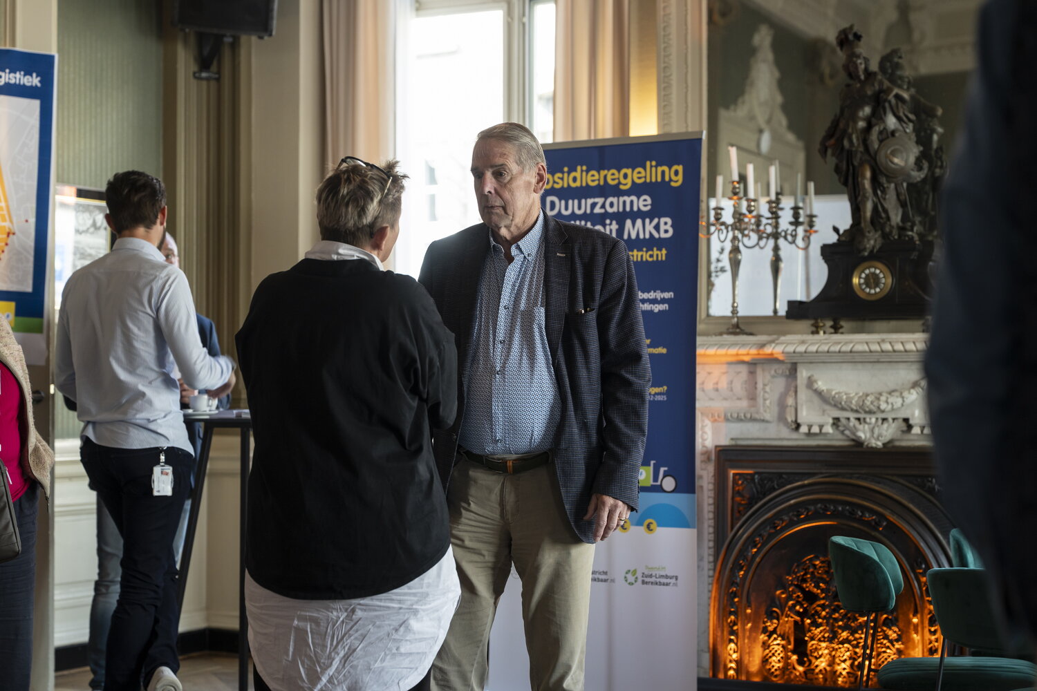 Twee mensen zijn in gesprek voor een banner van Stadslogistiek op de achtergrond 