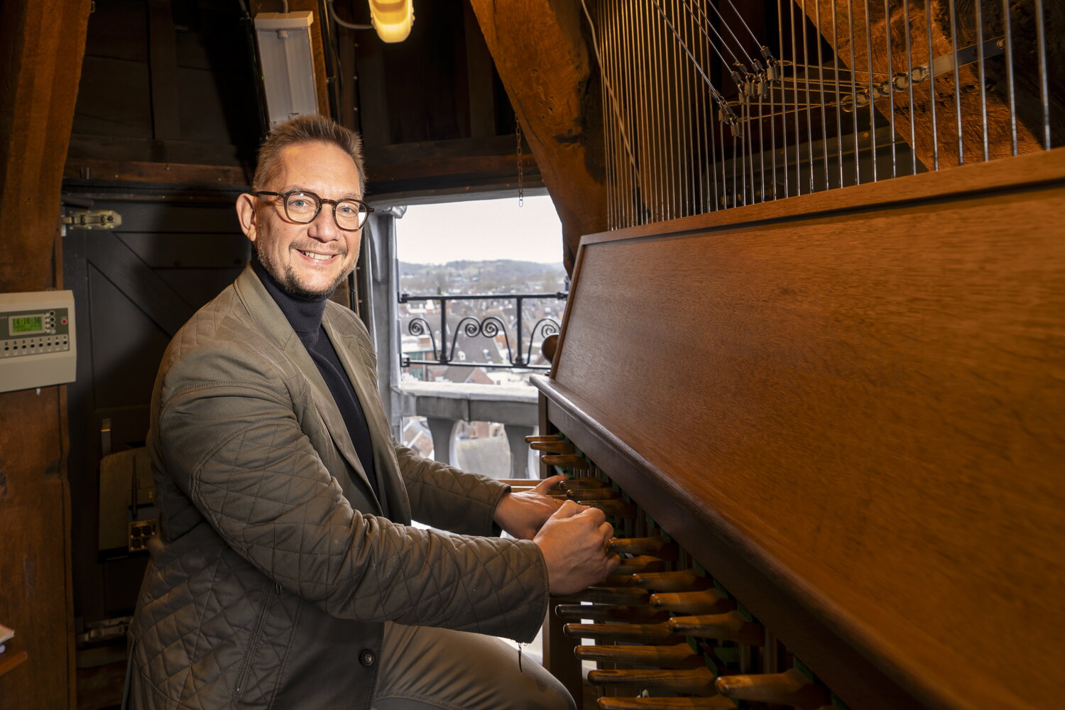 Frank Steijns zit in het gemeentehuis achter het carillon met Maastricht op de achtergrond