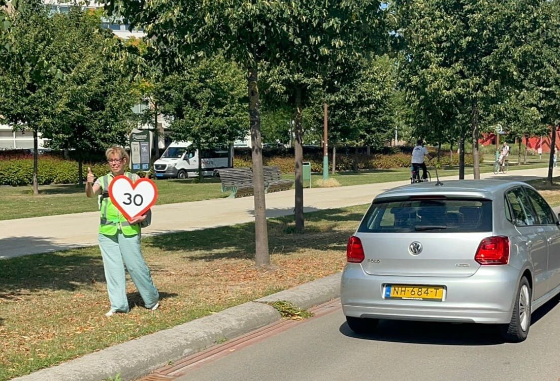 Duim omhoog, dertig rijden automobilisten Groene Loper, gewenste snelheid staat op bord dat door dame wordt vastgehouden