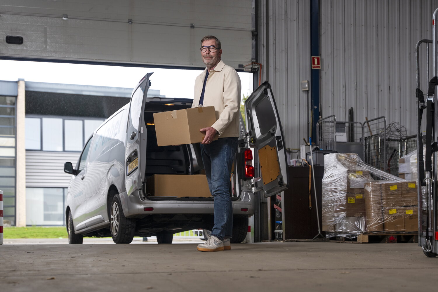 Man laadt dozen in in auto, in loods, werkt met goederenhubs
