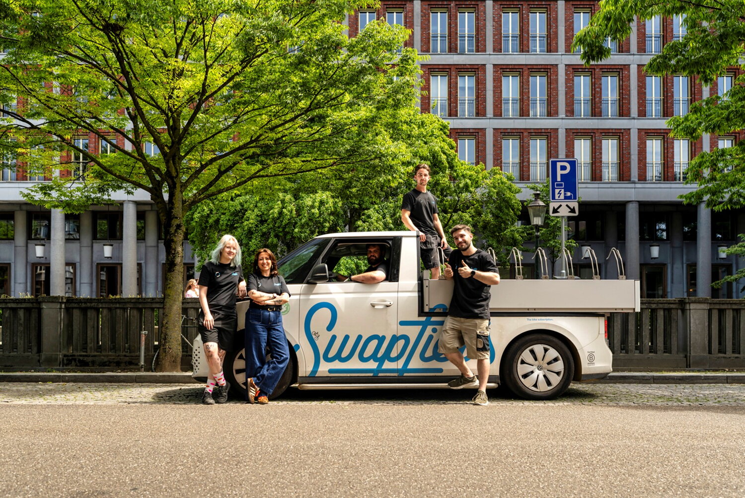 gaby met collega's swapfiets, mensen voor een grote strandwagen waarmee je fietsen kunt ophalen