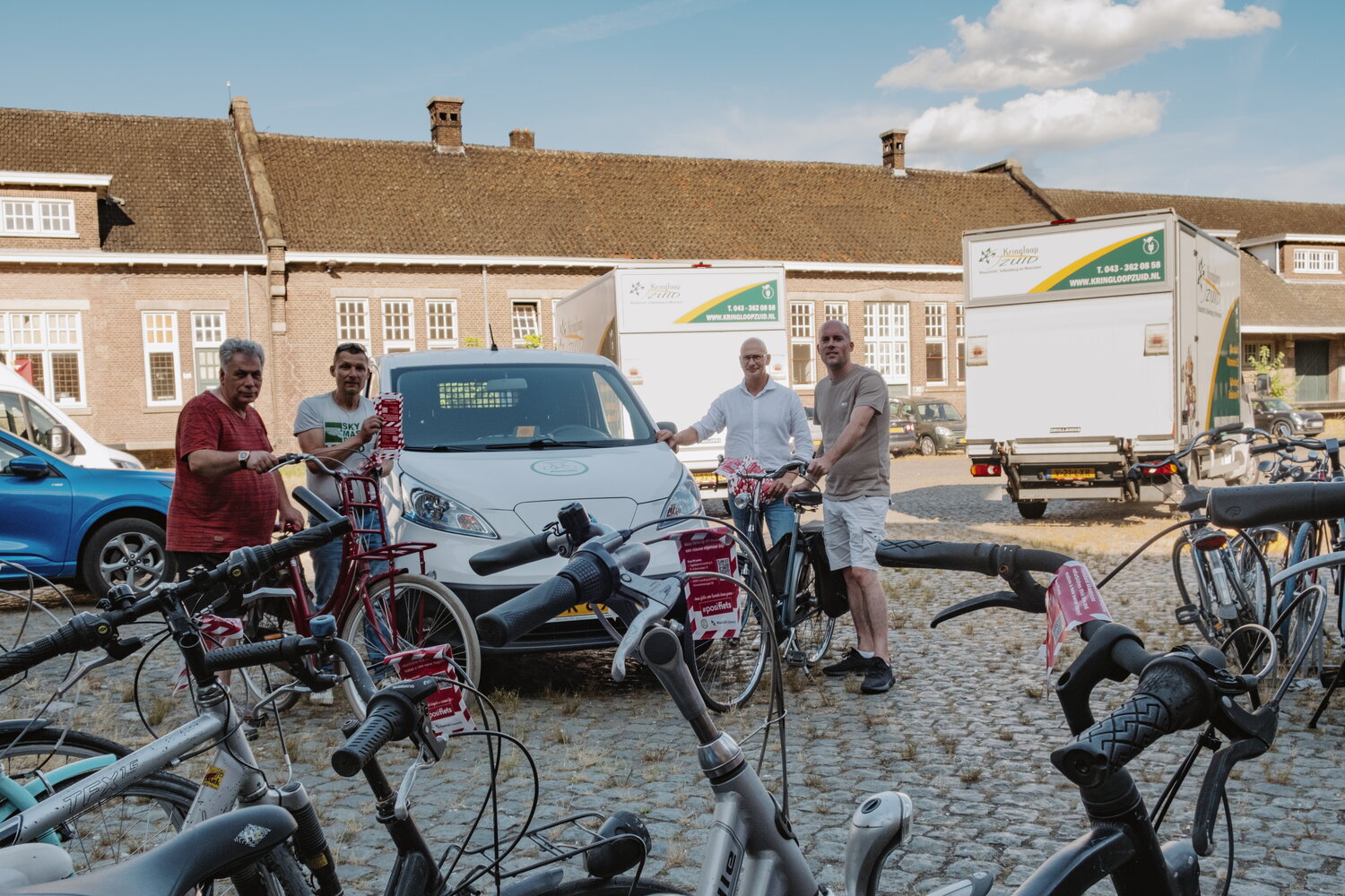 Kringloop en Fietsbank poseren trots met alle ingeleverde fietsen voor hun busjes.