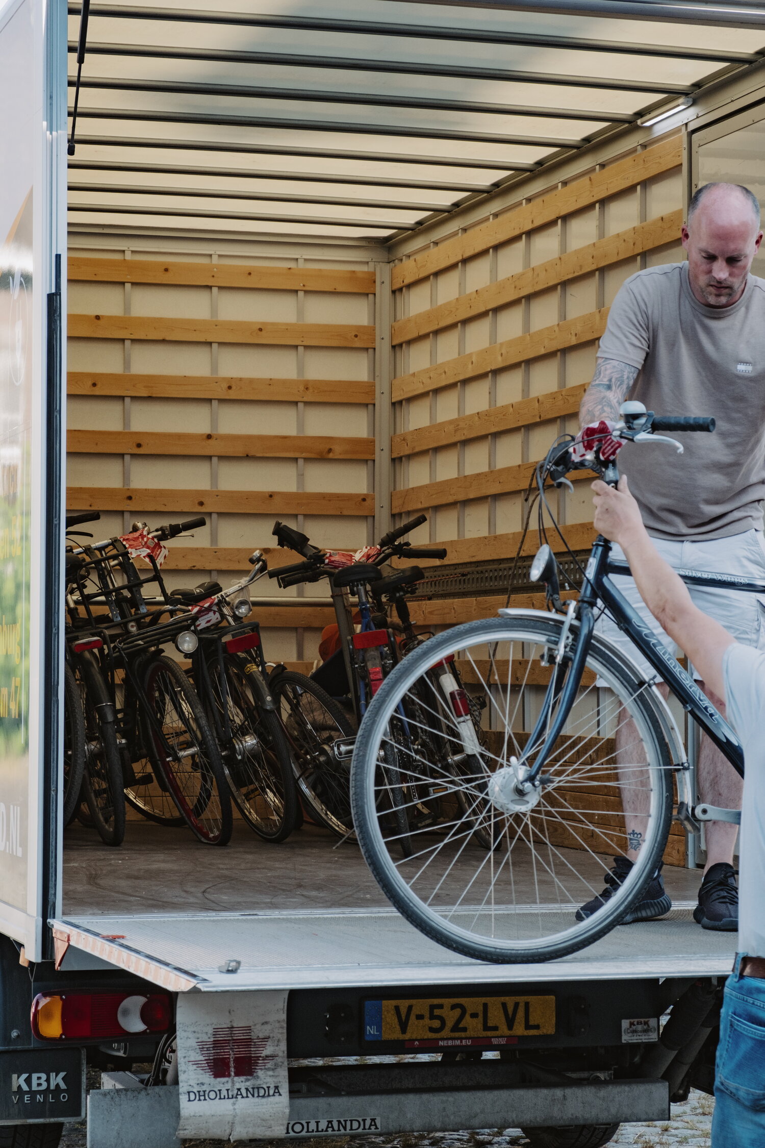 Medewerkers Kringloop en Fietsbank laden fietsen in busjes.