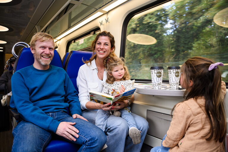 Gezin reist samen in de trein - vader, moeder en twee jonge meisjes zittend in de trein